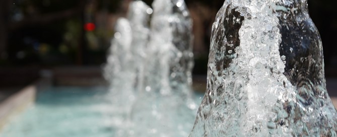 A closeup selective focus shot of a water fountain with trees on the background